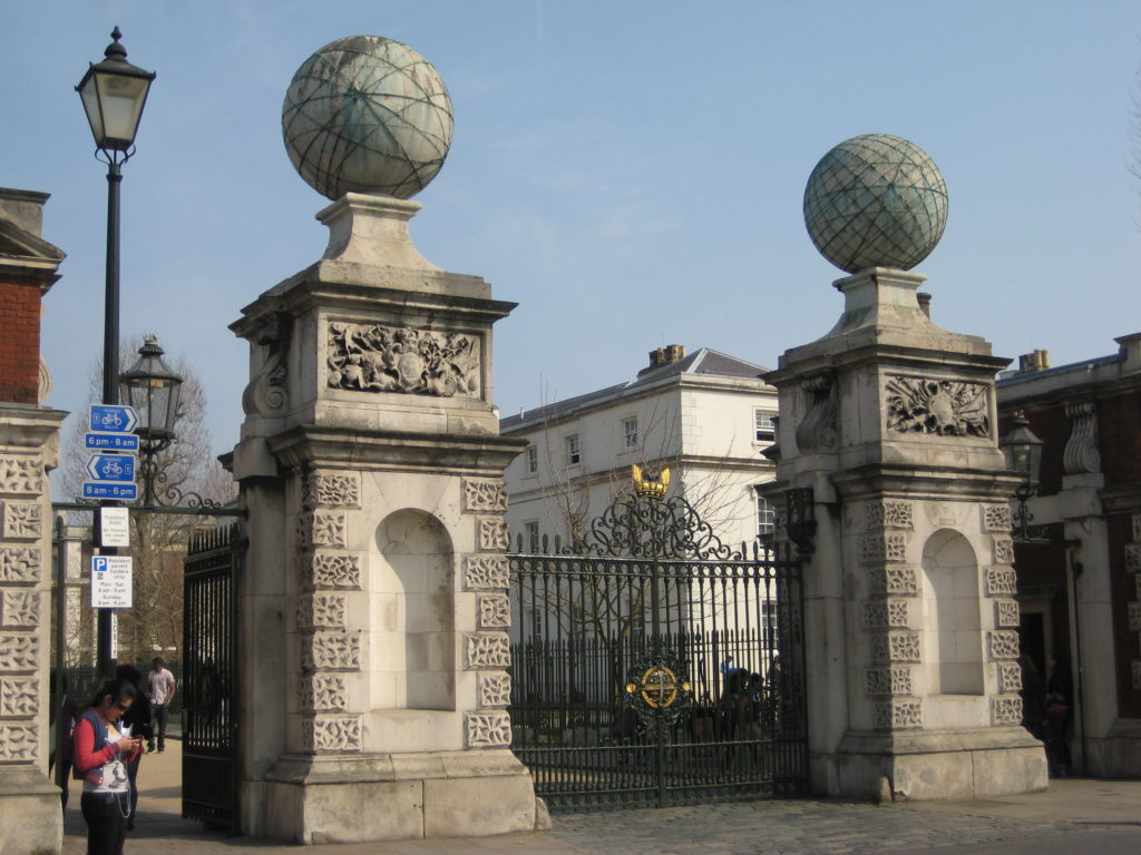 The twin gates at the old Naval college, Greenwich, England. Spheres atop rectangular stone columns. An iron gate in between.