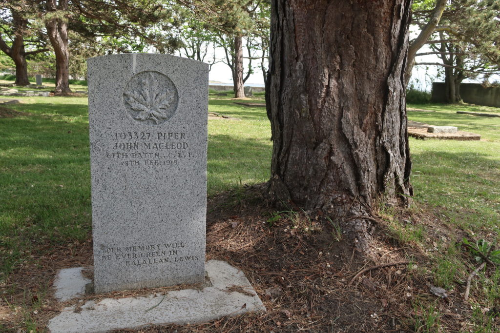 The lone grave of Piper John MacLeod next to a large tree at Ross Bay Cemetery, Victoria, B.C.